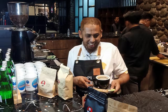 Umar Patek, a 58-year-old former militant who helped assemble the one-tonne bomb that killed 202 people in the 2002 Bali nightclub bombing, carries a cup of coffee at a cafe in Surabaya, East Java province, Indonesia, June 3, 2025. REUTERS/Prasto Wardoyo 