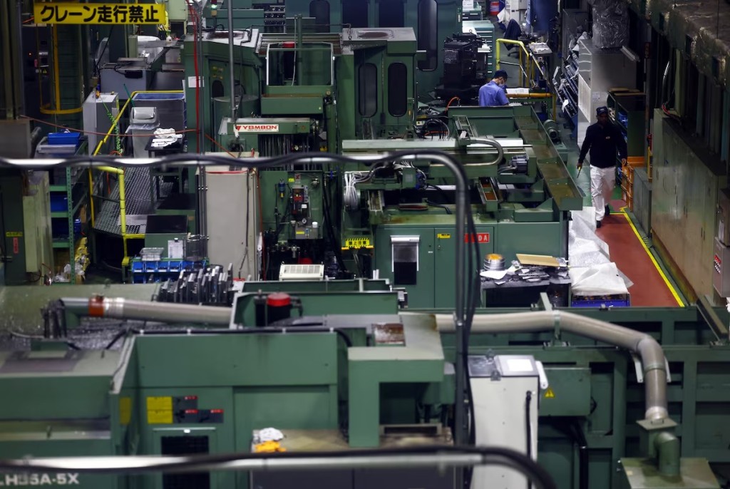 Workers walk between precision-machining machines for automotive parts inside a factory at Kyowa Industrial Co. in Takasaki, Gunma Prefecture, Japan April 11, 2025. REUTERS