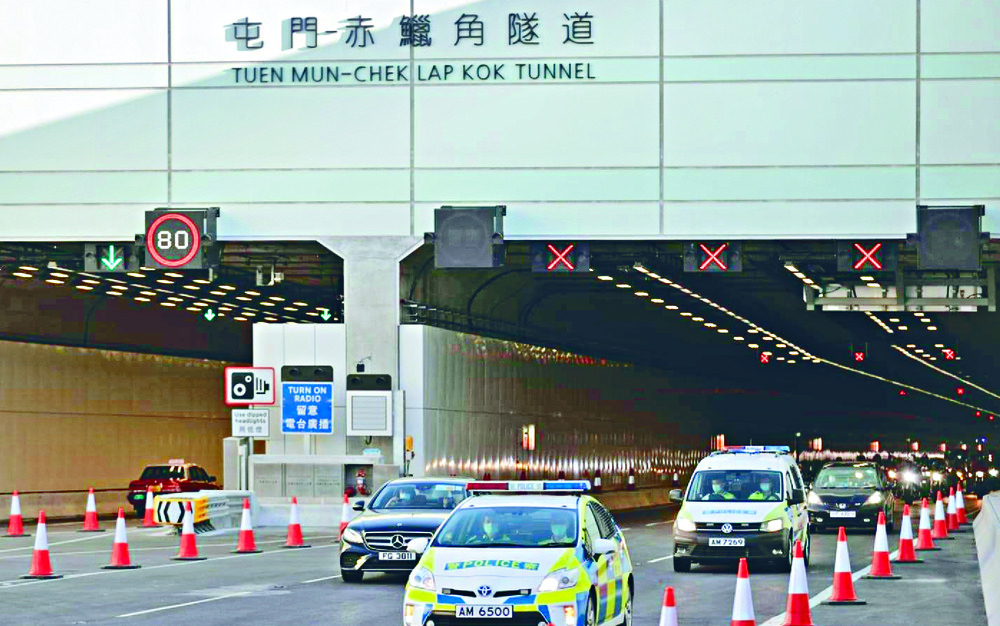 Police vehicles lead the first cars through the tunnel as long queues form. Sing Tao Police vehicles lead the first cars through the tunnel as long queues form. Sing Tao