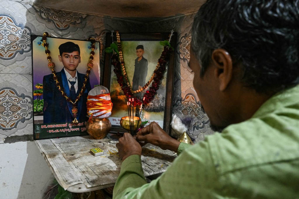 Photo by INDRANIL MUKHERJEE / AFP  In this photograph taken on November 8, 2025, Suresh Patni, father of Air India flight AI171 crash victim Akash Patni, offers prayers to his son's portraits at his residence in Ahmedabad.