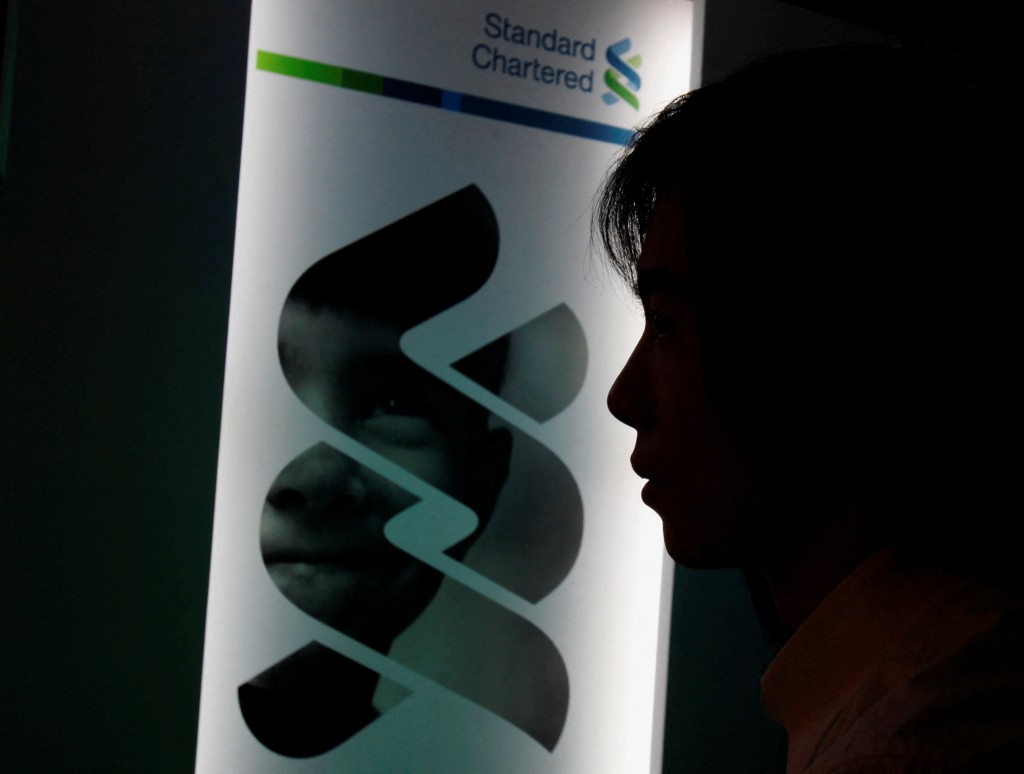 A journalist listens in front of a Standard Chartered bank logo in Hong Kong February 29, 2012.  REUTERS