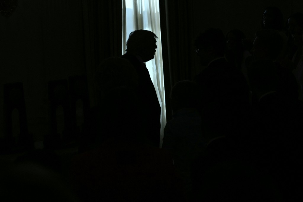 US President Donald Trump is silhouetted during the NCAA Collegiate National Champions Day at the White House in Washington, DC, on April 21, 2026. (Photo by Brendan SMIALOWSKI / AFP)