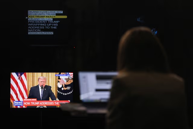 A journalist works as a screen displays U.S. President Donald Trump speaking about election security during an address to the nation from the East Room of the White House, in Washington, D.C., U.S., July 16, 2026. REUTERS/Kylie Cooper