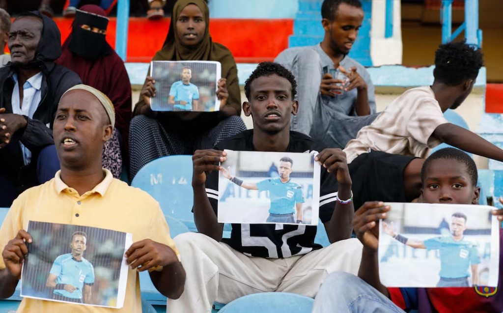 Somalis hold pictures of referee Omar Abdulkadir Artan, who had been expected to officiate matches at the 2026 FIFA World Cup but was refused entry to the United States, during a match between Gaadiidka and Juba at Mogadishu Stadium, in Mogadishu, Somalia, June 9, 2026. REUTERS/Feisal Omar