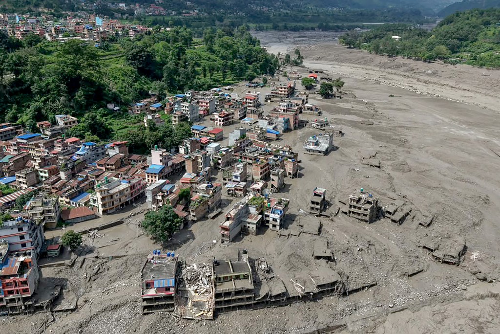 Houses lie partially submerged in muddy water along a riverside after flash floods in Nepal's Nuwakot district. (AFP)