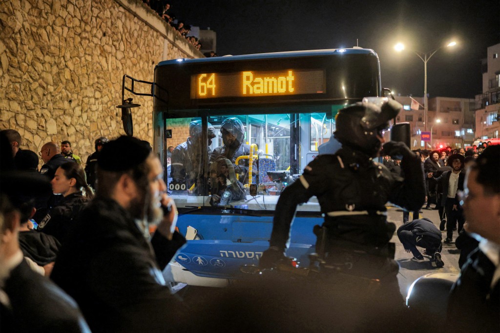 Photo by ILIA YEFIMOVICH / AFP  First responders surround a bus that reportedly ran over ultra-Orthodox Jewish men protesting against Israeli army conscription in Jerusalem on January 6, 2026.