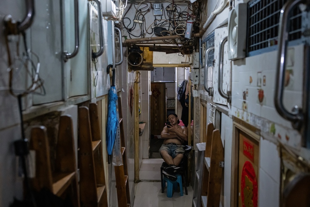 A resident of a 'coffin' home smokes in the corridor of a unit divided into upper and lower bunk-style compartments, housing about 20 people, in Hong Kong, China, July 10, 2024. REUTERS/Tyrone Siu A resident of a 'coffin' home smokes in the corridor of a unit divided into upper and lower bunk-style compartments, housing about 20 people, in Hong Kong, China, July 10, 2024. REUTERS/Tyrone Siu
