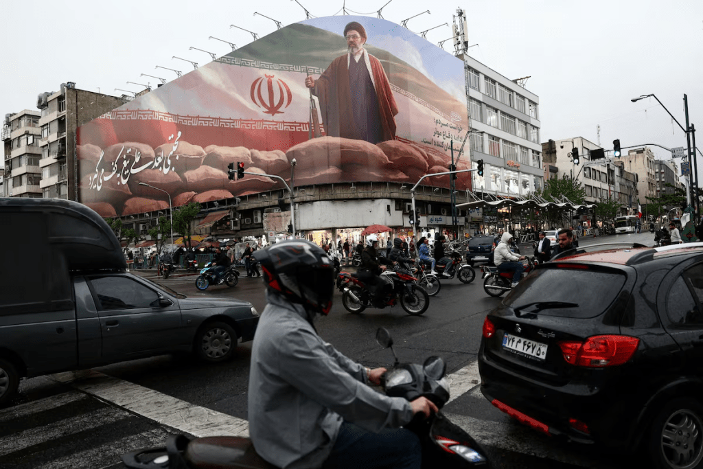 People ride motorcycles near a billboard featuring an image of Iran's new Supreme Leader Mojtaba Khamenei, amid a ceasefire between U.S. and Iran, in Tehran, Iran, April 20, 2026. Majid Asgaripour/WANA (West Asia News Agency) via REUTERS/File Photo 