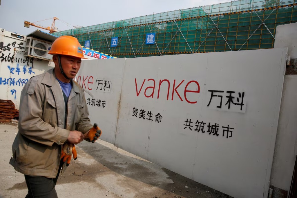 A person walks past by a gate with a sign of Vanke at a construction site in Shanghai, China, March 21, 2017. Picture taken March 21, 2017. REUTERS