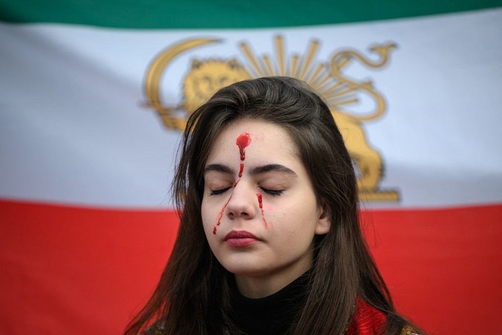 A protester has her face painted with fake blood during a demonstration to denounce the Iranian government's deadly crackdown on anti-government protesters in the Islamic Republic in Toulouse southwestern France on February 1, 2026. (Photo by Lionel BONAVENTURE / AFP)