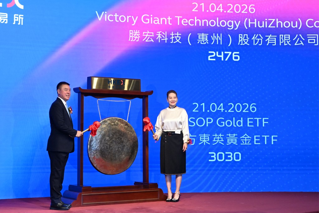 Chairman of Victory Giant Technology Chen Tao (L) and his wife Non-Executive Director Liu Chunlan (R) prepare to bang the gong to launch their company's IPO at the Hong Kong Exchanges and Clearing Limited (HKEX) In Hong Kong on April 21, 2026. (Photo by Peter PARKS / AFP)