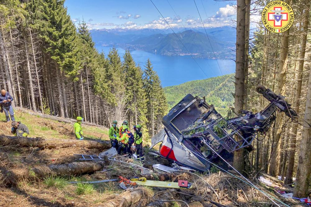Rescuers work by the wreckage of a cable car after it collapsed near the summit of the Stresa-Mottarone line in the Piedmont region, northern Italy, Sunday, May 23, 2022. A mountaintop cable car plunged to the ground in northern Italy on Sunday, killing at least nine people and sending at least three more to the hospital, authorities said Rescuers work by the wreckage of a cable car after it collapsed near the summit of the Stresa-Mottarone line in the Piedmont region, northern Italy, Sunday, May 23, 2022. A mountaintop cable car plunged to the ground in northern Italy on Sunday, killing at least nine people and sending at least three more to the hospital, authorities said