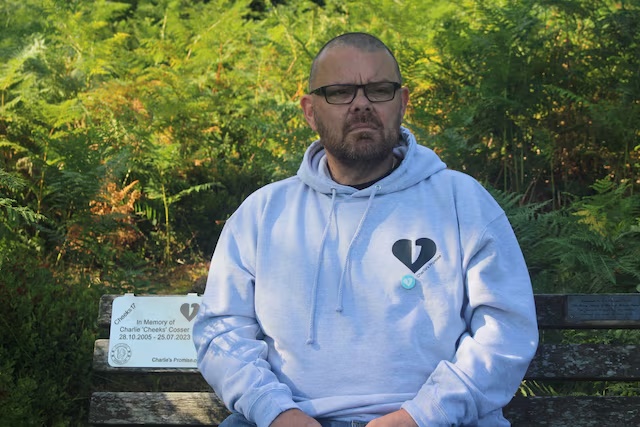 Martin Cosser sits on a memorial bench with a plaque honouring Charlie, Cosser's son, who was killed in a knife attack, at Devil's Punch Bowl, in Surrey, England, July 16, 2025. REUTERS/Catarina Demony/File Photo