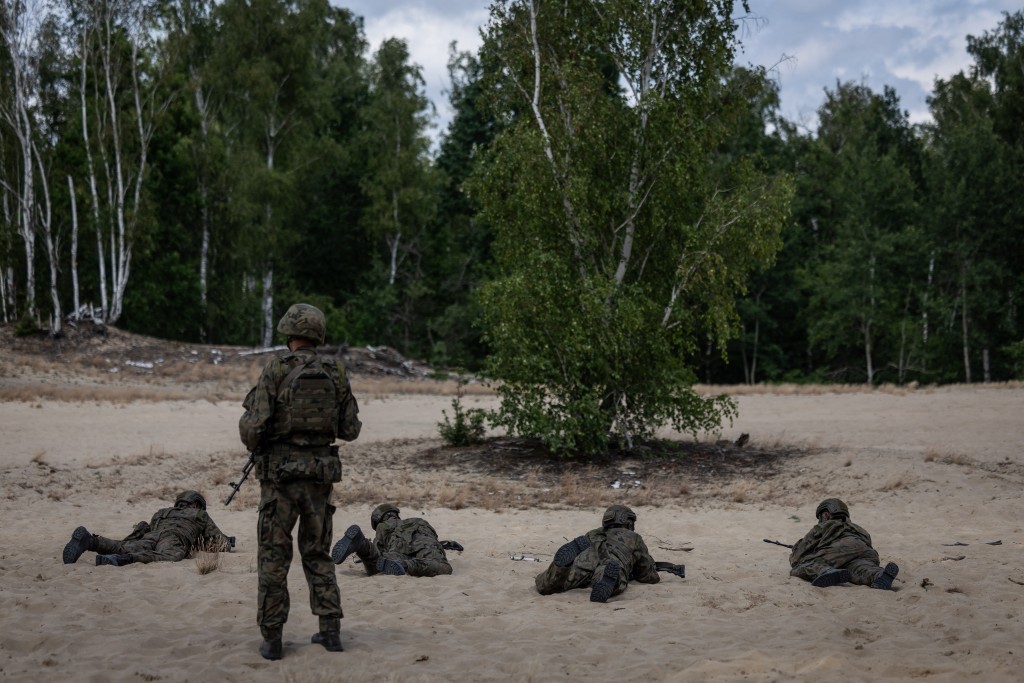 A military instructor keeps an eye on volunteers during a military training that is part of the "Vacation with the Army" project, at a military shooting range on the outskirts of Warsaw, Poland, on July 22, 2025.(Photo by Wojtek RADWANSKI / AFP)