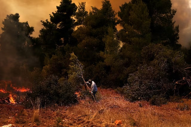 A resident battles a wildfire near the village Agia Paraskevi, Greece, August 2, 2026. REUTERS/Stelios Misinas 