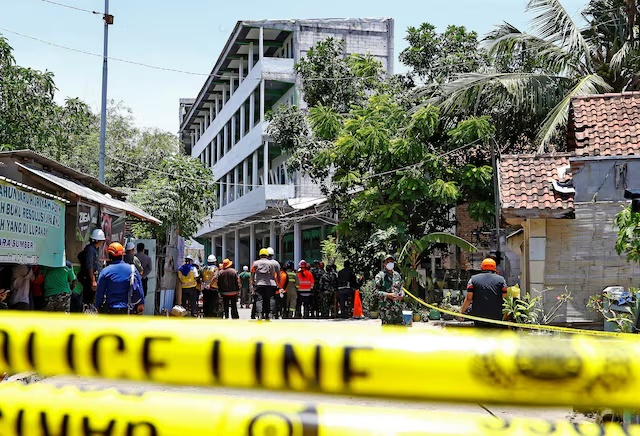 Rescuers gather near the site of a building collapse on Monday, where people remained trapped according to disaster mitigation agency, as the search and rescue operations continue at Al Khoziny Islamic boarding school in Sidoarjo, East Java province, Indonesia, October 2, 2025. REUTERS/Dipta Wahyu