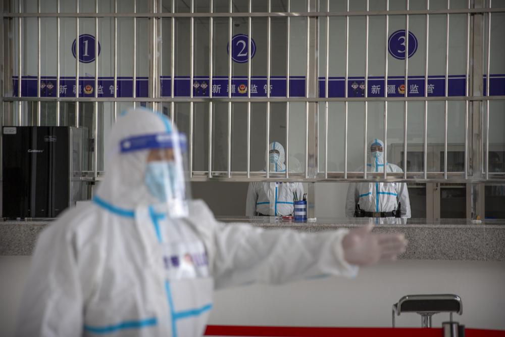 A security officer in a protective suit gestures as other officers stand at a reception area at the visitors' hall at the Urumqi No. 3 Detention Center in Dabancheng in western China's Xinjiang Uyghur Autonomous Region on April 23, 2021.