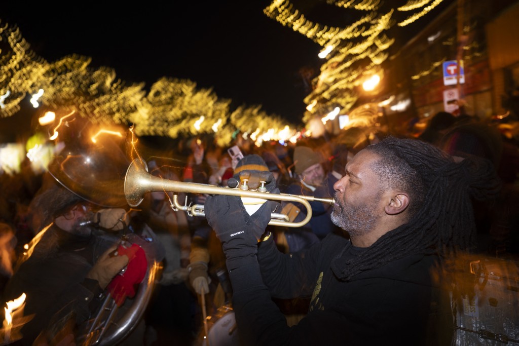 Photo by ROBERTO SCHMIDT / AFP  A musician blows into a trumpet as people gather for a candlelight vigil where 37-year-old Alex Pretti was fatally shot by immigration agents last week, in Minneapolis, Minnesota, on January 28, 2026.