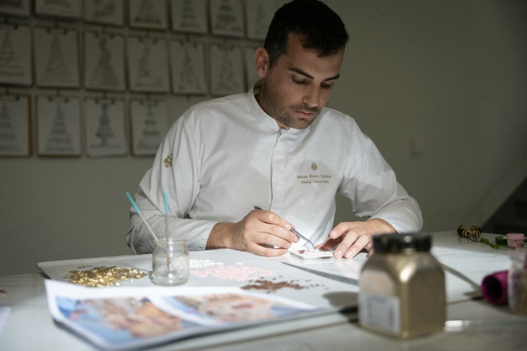 Photo by THOMAS SAMSON / AFP French pastry chef Bastien Blanc-Tailleur creates decorations for a wedding cake at his studio in Saint-Remy-les-Chevreuse, southwestern Paris on April 10, 2026.