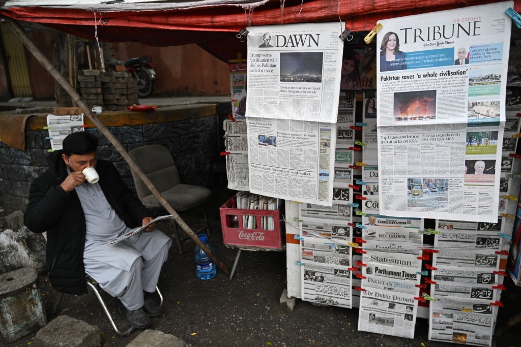 Photo by AAMIR QURESHI / AFP  A vendor drinks tea as he read a morning newspaper at a roadside stall in Islamabad on April 8, 2026.
