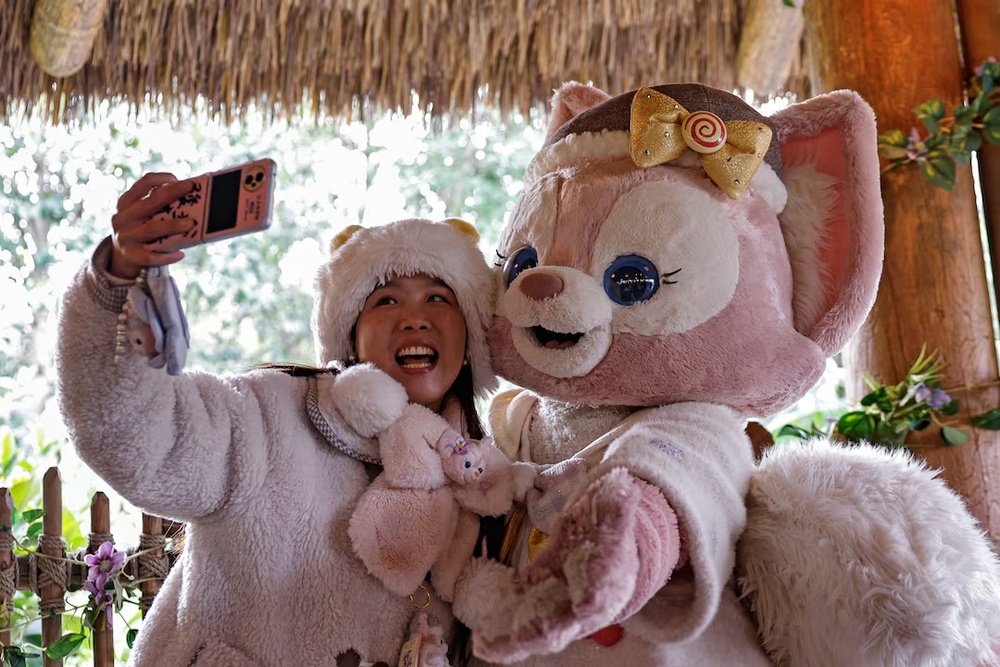 A fan takes a selfie with a performer dressed as the character LinaBell, a pink fox character from the Disney series 'Duffy and Friends', at Shanghai Disneyland, in Shanghai, China December 23, 2024. REUTERS/Tingshu Wang A fan takes a selfie with a performer dressed as the character LinaBell, a pink fox character from the Disney series 'Duffy and Friends', at Shanghai Disneyland, in Shanghai, China December 23, 2024. REUTERS/Tingshu Wang