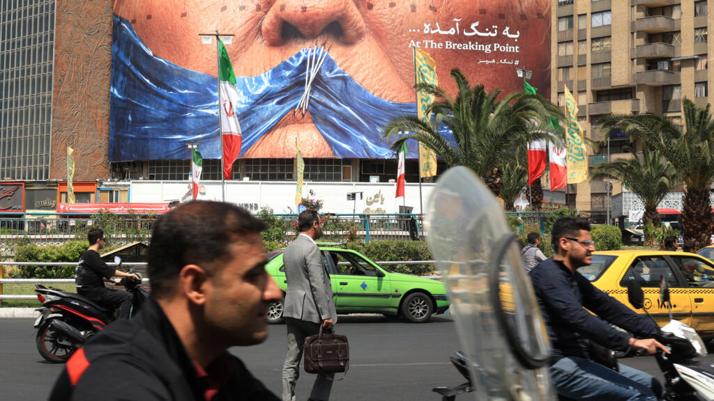 Commuters make their way past an anti-US billboard referring to President Donald Trump and the Strait of Hormuz, installed on a building in Tehran © - / AFP