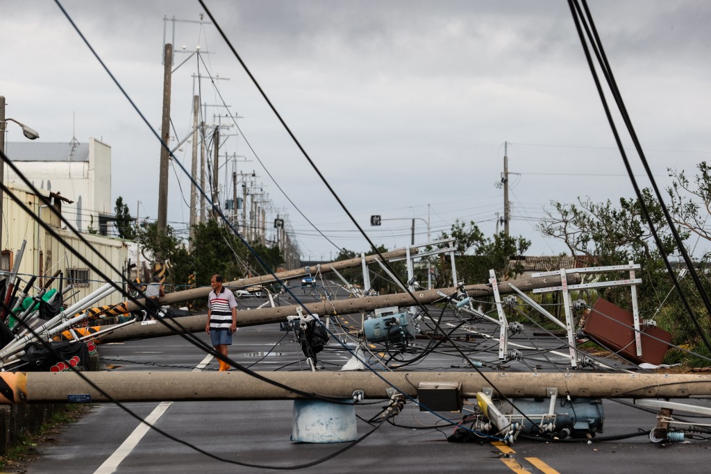 A man walks among utility poles knocked down during Typhoon Danas in Tainan on July 7, 2025. (AFP)