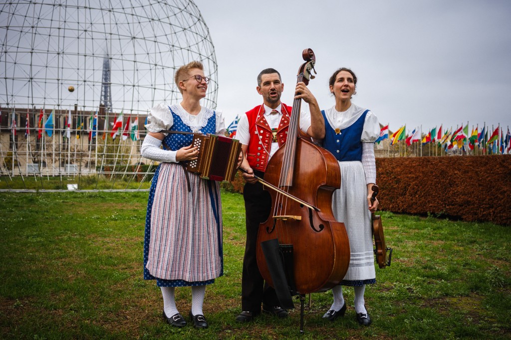 Members of the Trio 'Rond Om de Santis', yodel musicians Katja Burgler (L), Maya Stieger (R) and Peter Looser perform in the garden of the UNESCO headquarters in Paris on November 27, 2025. (Photo by Dimitar DILKOFF / AFP)