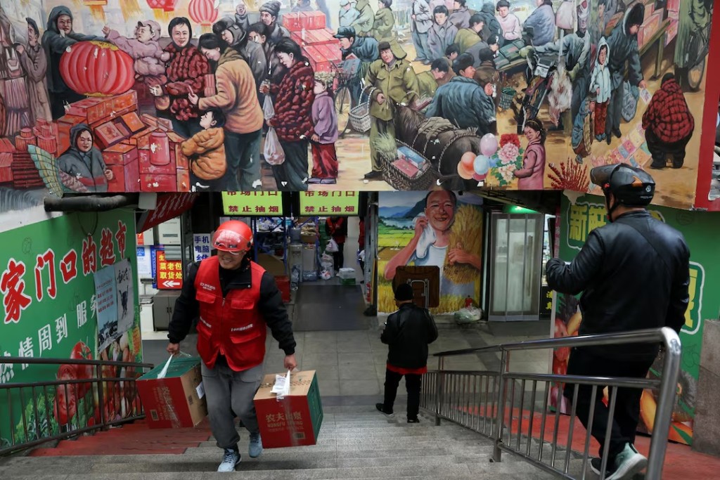 A JD.com delivery worker picks up grocery orders from a market in Beijing, China October 17, 2024. REUTERS/Florence Lo/ File Photo