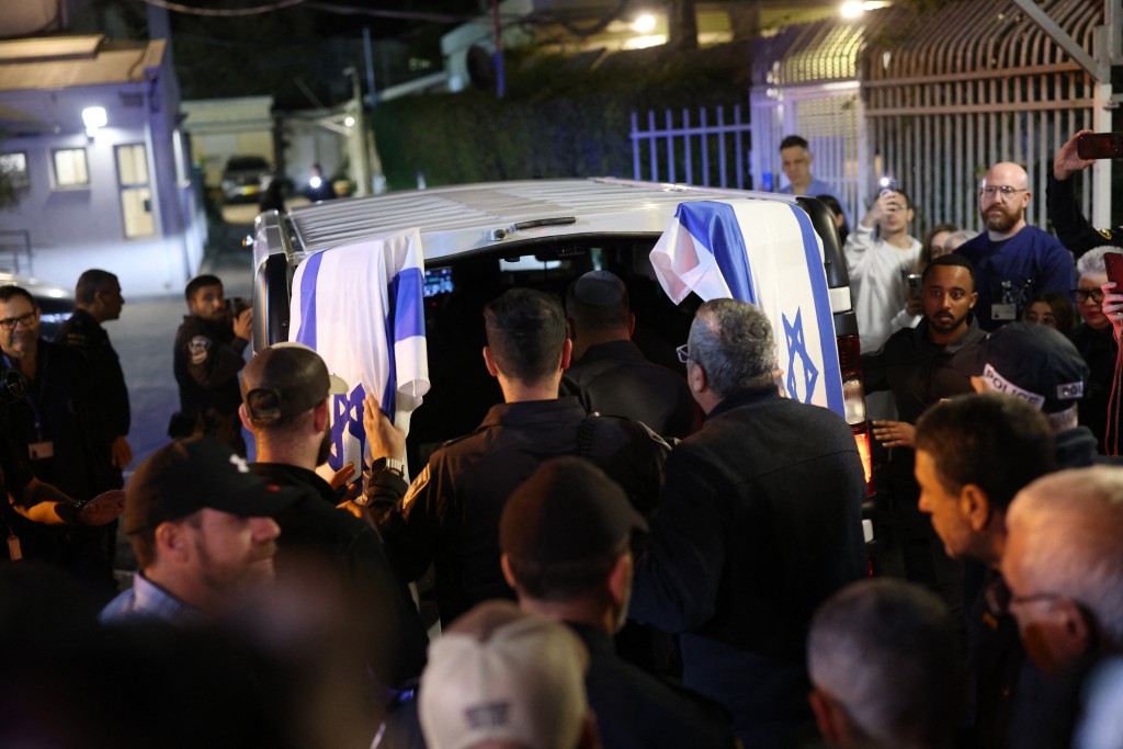 Photo by ILIA YEFIMOVICH / AFP  Israeli police officers pay their respects outside of the Abu Kabir Forensic Institute, as the body of last Israeli hostage arrives in Tel Aviv on January 26, 2026.