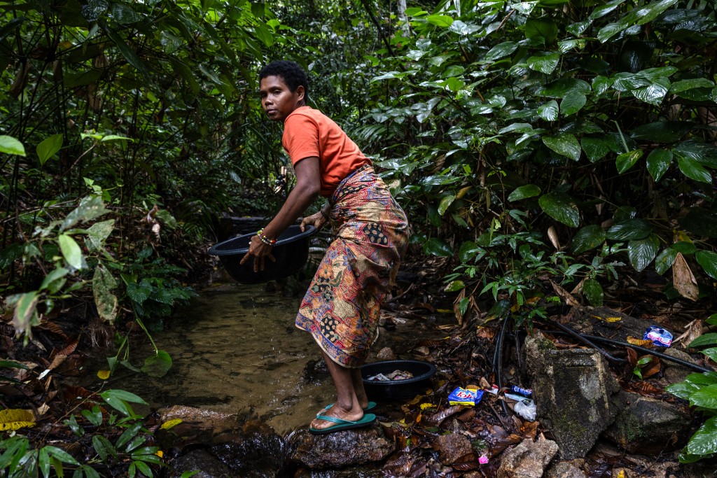 Photo by LUKE DUGGLEBY / COURTESY OF LUKE DUGGLEBY / AFP  This handout courtesy of Luke Duggleby taken on August 11, 2025 and released to AFP on October 30 shows a Maniq woman collecting water from a stream near to their camp in order to wash clothes in Phatthalung in southern Thailand.