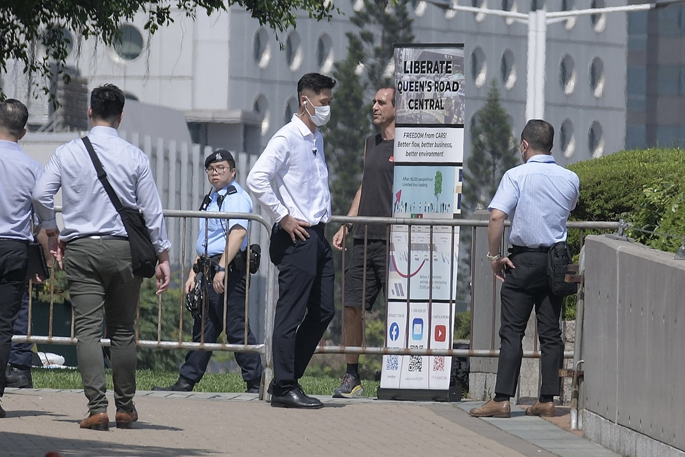 The expat is pulled down after trying to climb a lamppost and escorted to Tamar Park. SING TAO The expat is pulled down after trying to climb a lamppost and escorted to Tamar Park. SING TAO