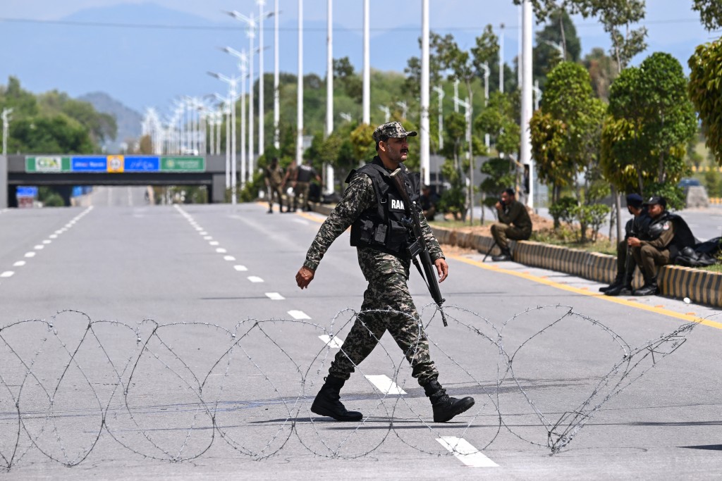 Photo by FAROOQ NAEEM / AFP  A Pakistani Ranger walks past barbed wire spread over a road near the expected venue of the US-Iran talks in the Red Zone area of Islamabad on April 10, 2026.