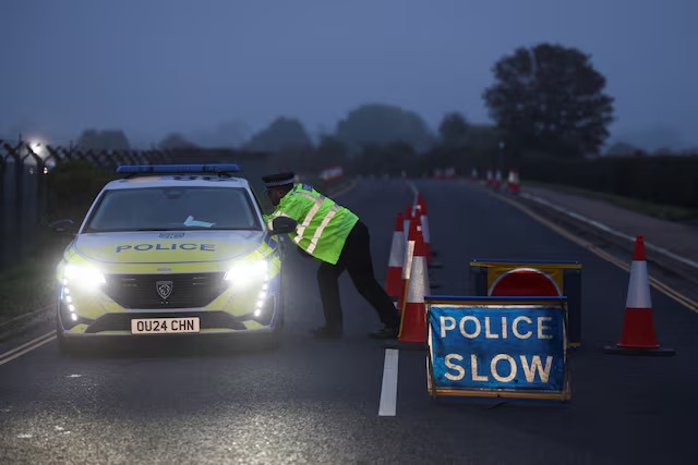 A police officer guards an area as roadblocks remain in place near RAF Fairford airbase, after police declared a major incident at the base and arrested several men on suspicion of offences under the Explosives Act, who have since been released on bail, in Fairford, Gloucestershire, Britain, September 29, 2026. REUTERS/Toby Shepheard