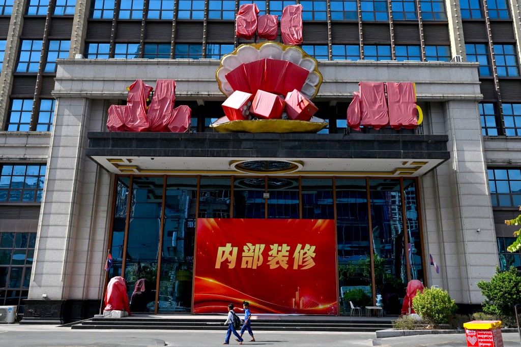 Photo by TANG CHHIN SOTHY / AFP  People walk past the main Jinbei Casino, currently under renovation and part of a suspected compound built and operated by internationally sanctioned accused scam boss Chen Zhi's Prince Group, in Sihanoukville on January 14, 2026.
