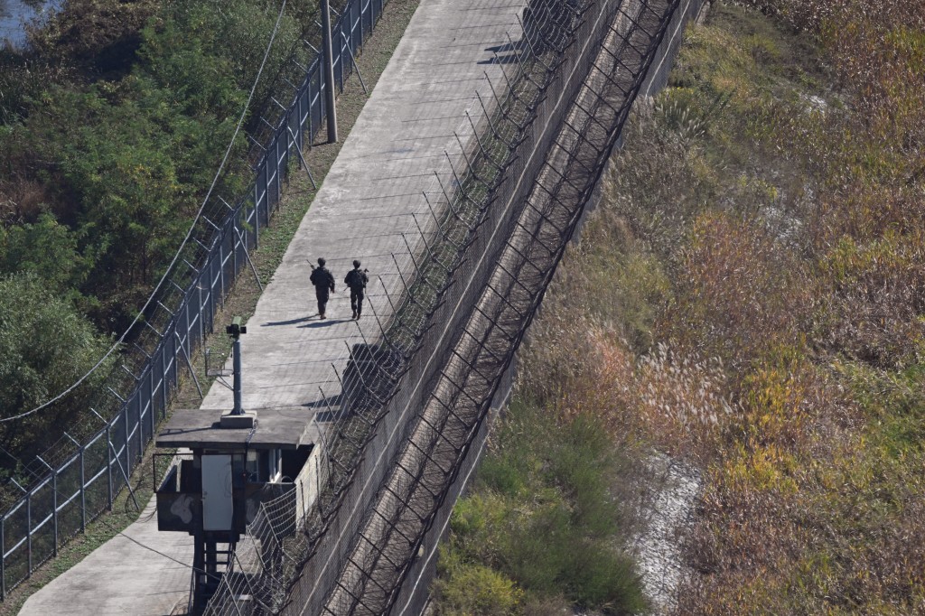 Photo by JUNG YEON-JE / AFP  South Korean soldiers patrol along a military fence on the south side of the Demilitarised Zone (DMZ) dividing the two Koreas, as seen from a South Korean observatory in the border city of Paju on October 20, 2026.