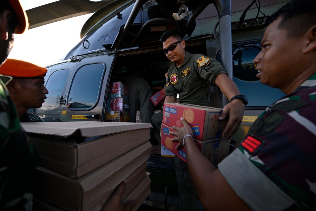 Photo by CHAIDEER MAHYUDDIN / AFP  Indonesian air force personnel load supplies, which will be distributed to residents in flood-affected areas, into a helicopter in Sultan Iskandar Muda, Blang Bintang on December 4, 2025.