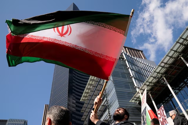 A demonstrator waves an Iranian flag during a "No War on Iran" rally outside of City Hall in Seattle, Washington, U.S., April 7, 2026. REUTERS/David Ryder
