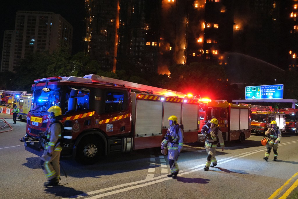 Photo by TOMMY WANG / AFP  Firefighters work at the scene as a major fire engulfs several apartment blocks at the Wang Fuk Court residential estate (background) in Hong Kong's Tai Po district on November 26, 2025.