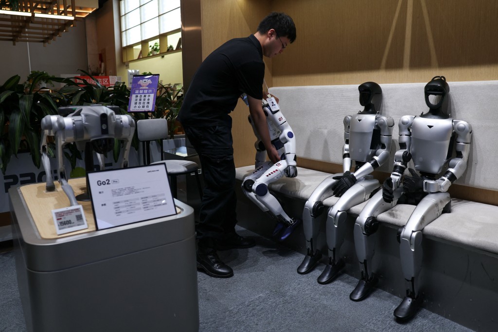 A staff member places a Unitree's R1 humanoid robot back in its seat at a Unitree store in Beijing, China, August 1, 2026. REUTERS/Tingshu Wang