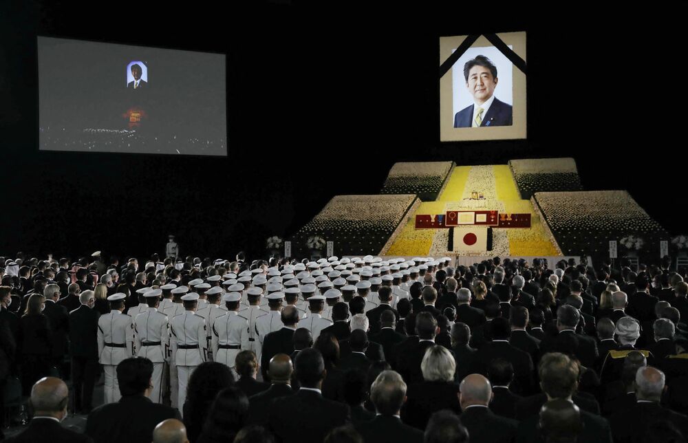 Shinzo Abe's widow, Akie, carries the remains of the former prime minister as she walks behind Fumio Kishida at the ceremony attended by Crown Prince Akishino, bottom left, Kamala Harris and other guests. Many also protested the event. AFP, REUTERS, 