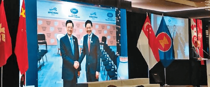 Ong Siew Gay speaks at a reception to mark Singapore's upcoming 60th National Day with an image of Chief Executive John Lee and Singaporean Prime Minister and Minister for Finance Lawrence Wong in the backdrop.