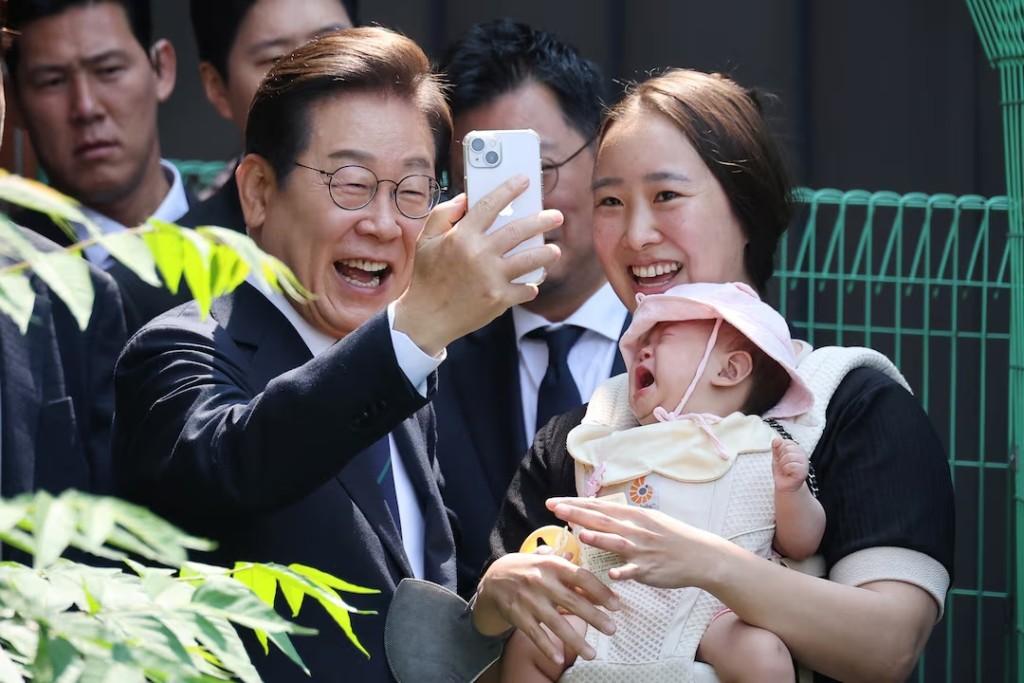 Lee Jae-myung, the presidential candidate for South Korea's Democratic Party, takes a selfie with his supporter as he leaves a polling station after casting his early vote for the upcoming presidential election in Seoul, South Korea, May 29, 2025. REUTERS/Kim Hong-Ji TPX IMAGES OF THE DAY