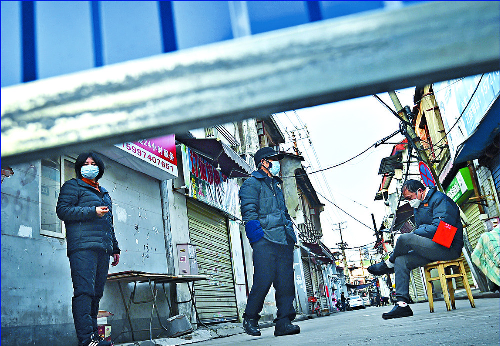 A volunteer sits on a chair to keep guard near barricades blocking a residential area in Wuhan. AP A volunteer sits on a chair to keep guard near barricades blocking a residential area in Wuhan. AP