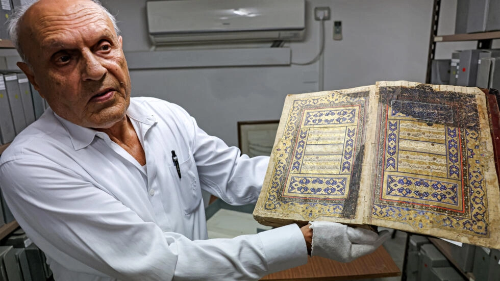 Librarian Khader Salameh with a gilded copy of the Koran from the 16th century. (AFP) Librarian Khader Salameh with a gilded copy of the Koran from the 16th century. (AFP)
