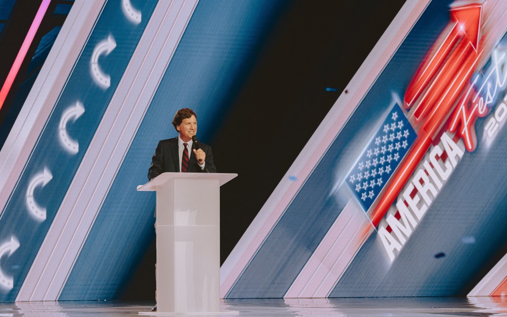 Photo by OLIVIER TOURON / AFP  Conservative political commentator and podcast host Tucker Carlson speaks at Turning Point's annual AmericaFest conference, in remembrance of late right-wing political activist Charlie Kirk, in Phoenix, Arizona on December 18, 2025.