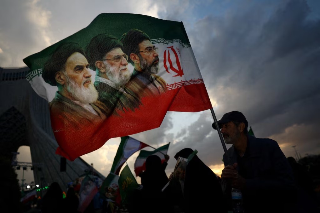  A man holds a flag with a picture of late leader of the Islamic Revolution Ayatollah Ruhollah Khomeini, late Supreme Leader of Iran Ayatollah Ali Khamenei and Iran's new Supreme Leader Mojtaba Khamenei, during a rally in Tehran, Iran, April 29, 2026. Majid Asgaripour/WANA (West Asia News Agency) via REUTERS/File Photo 