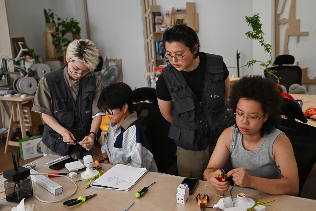 Photo by PEDRO PARDO / AFP  This picture taken on June 28, 2026 shows Wu Shuang (C) and Wang Risun (L) giving an electricity course to a group of women at the Mulan Build workshop in Hangzhou, in eastern China's Zhejiang province.