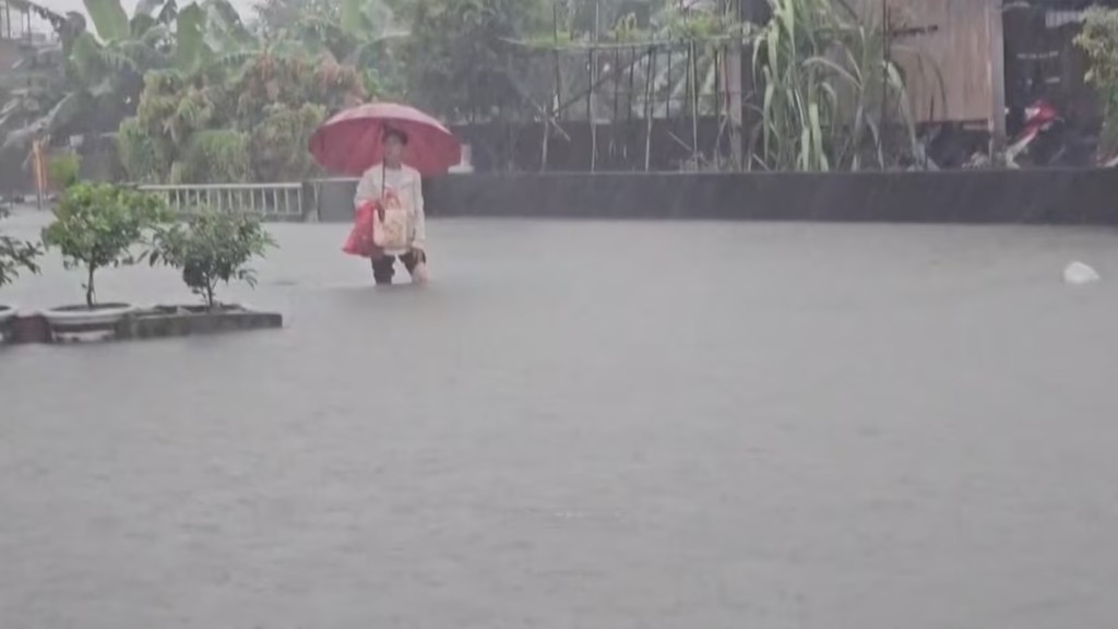 A man with an umbrella stands in the floodwater during heavy rains caused by the nearby passing of typhoon Mekkhala, as it heads towards Japan, in Pingtung, Taiwan, June 25, 2026, in this screen grab taken from a video. CTS via REUTERS TV/via REUTERS