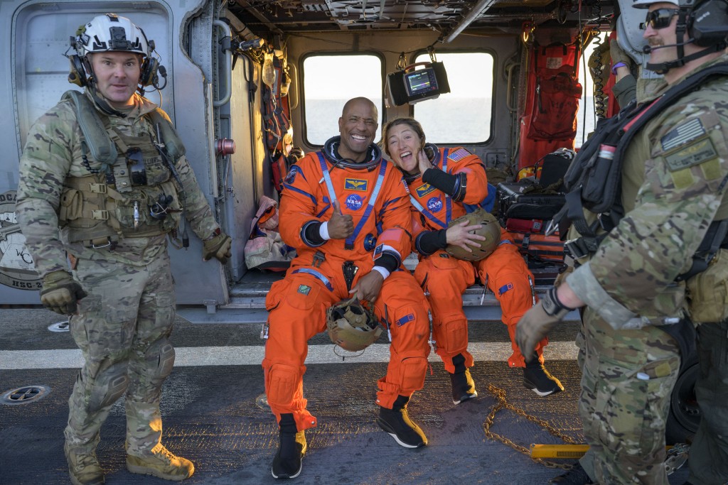 Photo by BILL INGALLS / NASA / AFP  This handout photo released by NASA shows NASA astronaut Victor Glover (L), Artemis II pilot, and NASA astronaut Christina Koch, Artemis II mission specialist, sitting on a Navy MH-60 Seahawk from Helicopter Sea Combat Squadron (HSC) 23 on the flight deck of USS John P. Murtha after they and fellow crewmates were extracted from their Orion spacecraft after splashdown, April 10, 2026, in the Pacific Ocean off the coast of California.